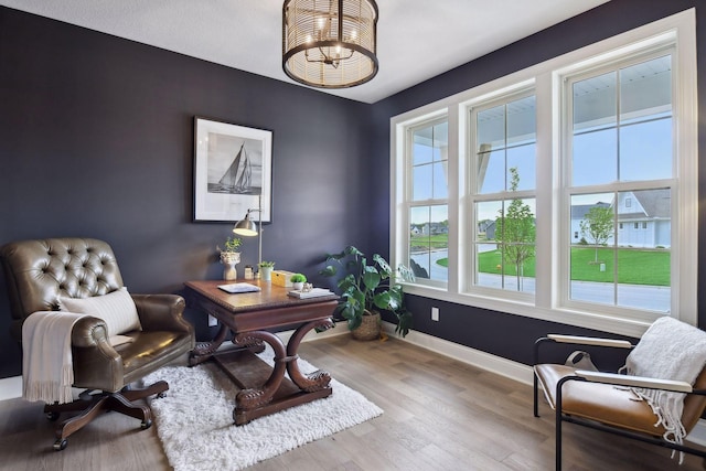 office area with light wood-type flooring, a notable chandelier, and baseboards