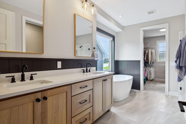 bathroom featuring a bathtub, double vanity, and tile patterned flooring