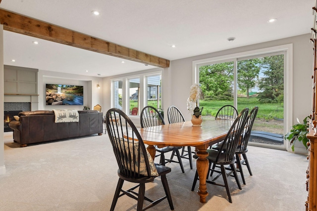 carpeted dining room featuring a fireplace and beamed ceiling