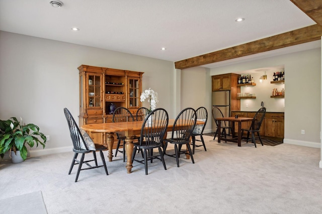 carpeted dining room featuring beamed ceiling and bar area