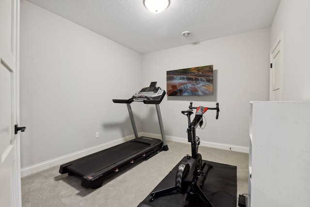 exercise area featuring a textured ceiling and carpet flooring