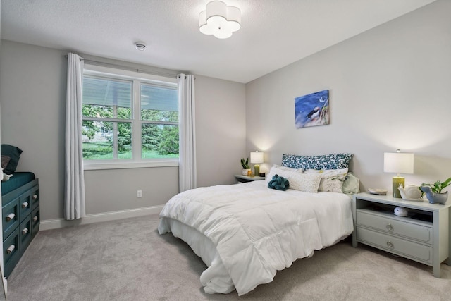 bedroom featuring light colored carpet, a textured ceiling, and baseboards