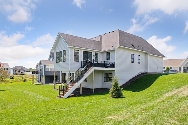 back of property featuring a yard, stairway, a wooden deck, and roof with shingles