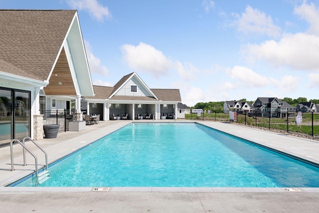 community pool with a residential view, a patio area, and fence