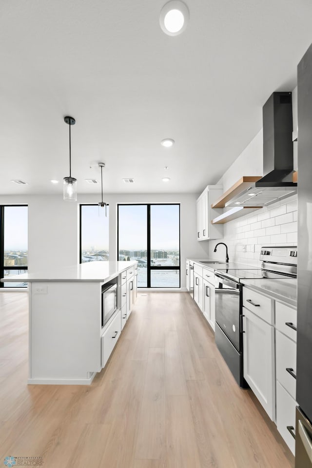 kitchen with black microwave, a kitchen island, stainless steel range with electric cooktop, and white cabinets