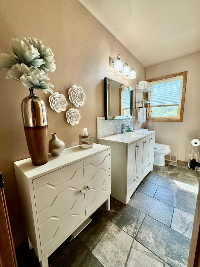 bathroom featuring vanity, toilet, and tasteful backsplash