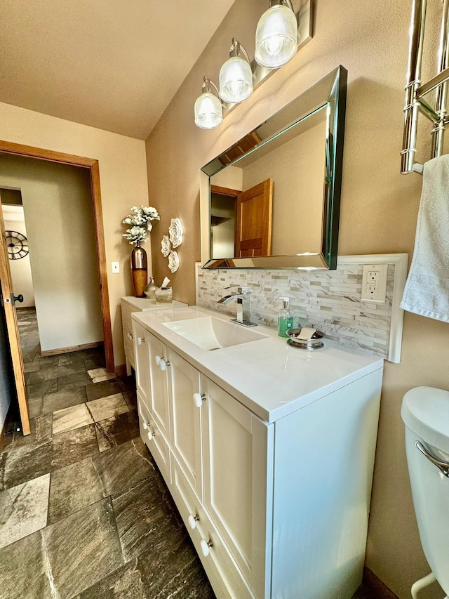 bathroom with vanity, toilet, and tasteful backsplash