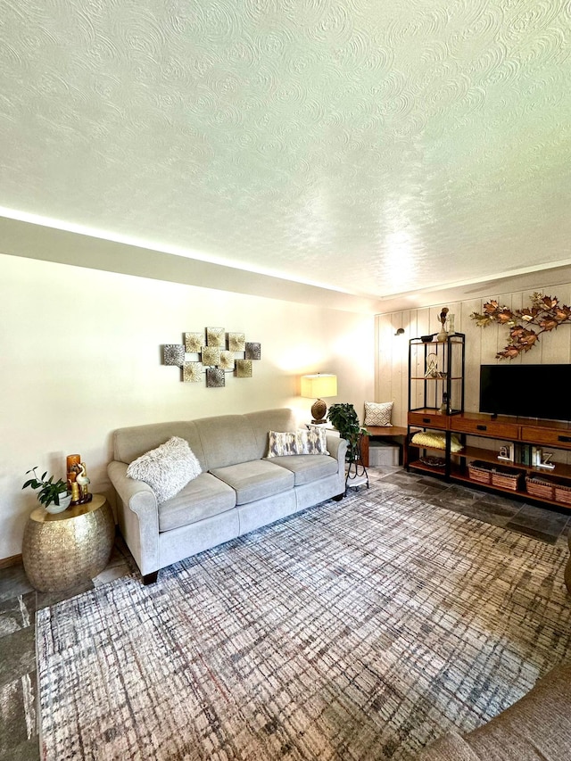 living room with wood walls, a textured ceiling, and carpet floors