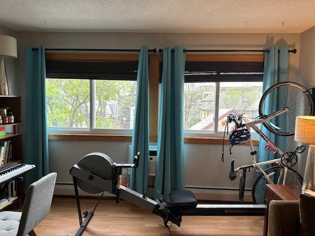 exercise room featuring a textured ceiling and light wood-type flooring