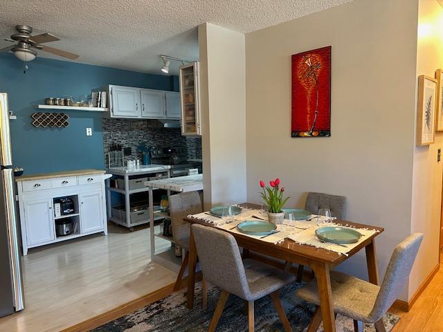 dining room featuring ceiling fan, light hardwood / wood-style flooring, a textured ceiling, and rail lighting