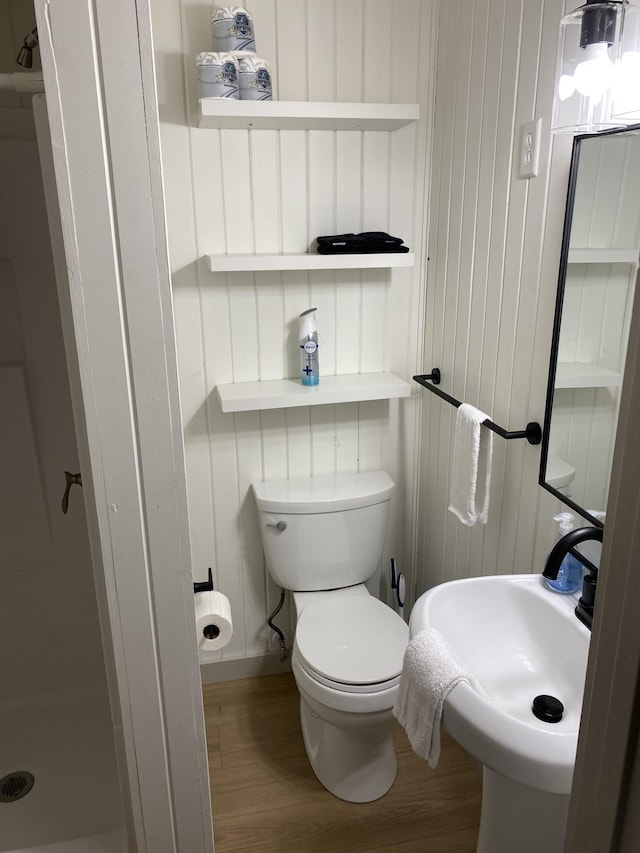 bathroom featuring toilet, a sink, walk in shower, and wood finished floors