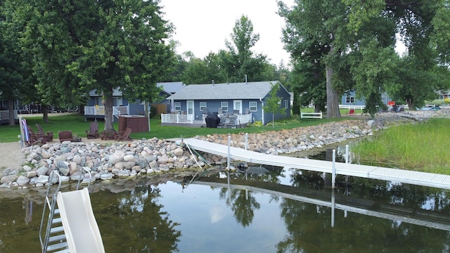 view of dock with a yard and a deck with water view