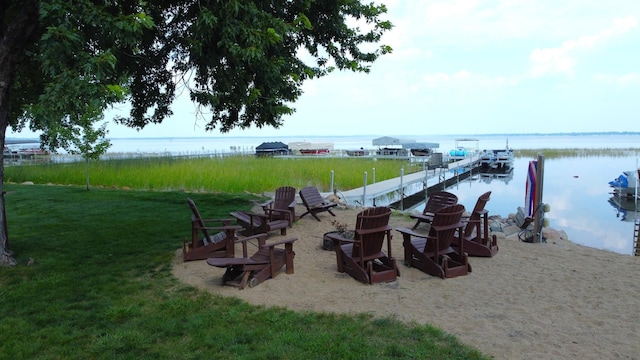 exterior space with a fire pit, a dock, a water view, and a lawn