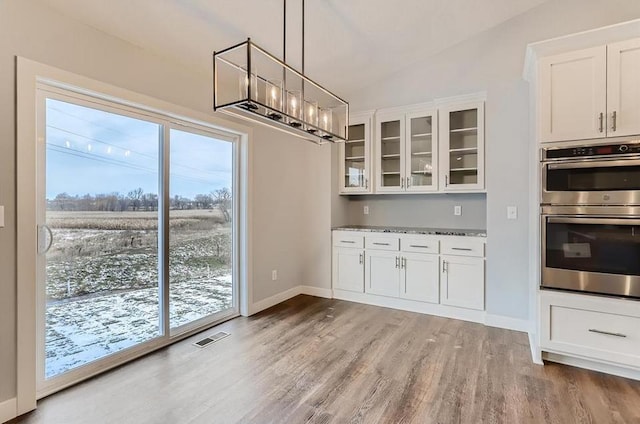 unfurnished dining area with light hardwood / wood-style flooring, lofted ceiling, and a chandelier