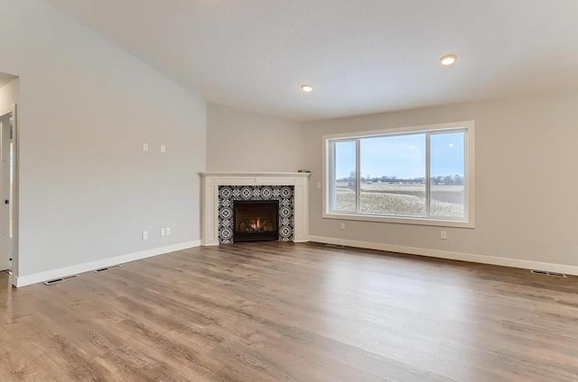 unfurnished living room featuring wood-type flooring and a tile fireplace