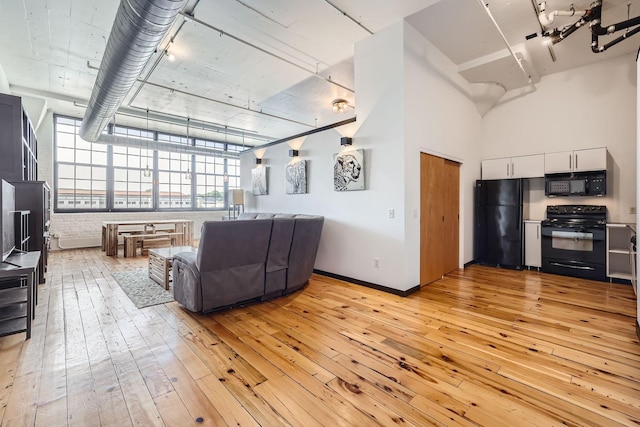 living room featuring a high ceiling and light hardwood / wood-style flooring