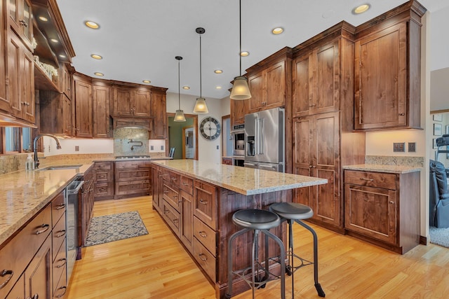 kitchen featuring stainless steel appliances, a sink, a kitchen breakfast bar, a center island, and pendant lighting