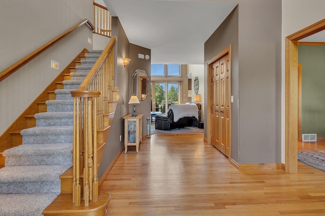 foyer entrance featuring light wood-style flooring, stairs, visible vents, and baseboards