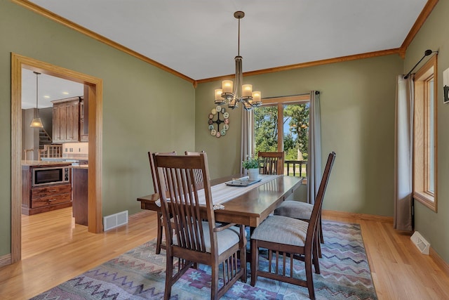 dining area featuring visible vents, crown molding, and light wood finished floors