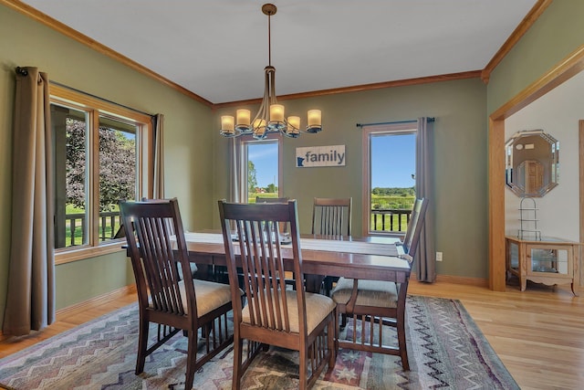 dining space with light wood-style floors, baseboards, crown molding, and an inviting chandelier