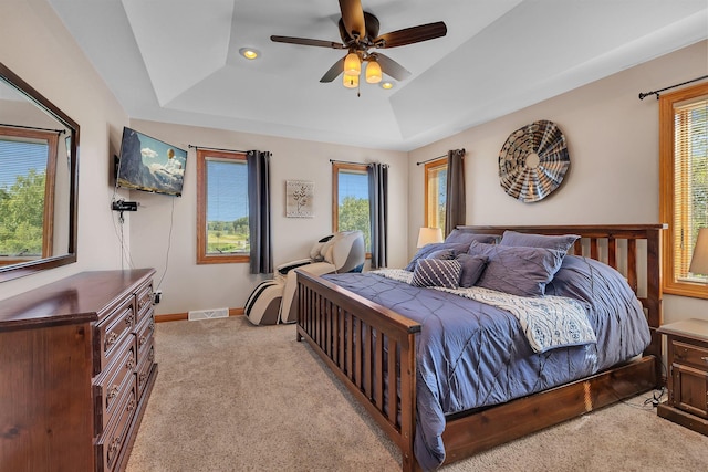 bedroom featuring baseboards, visible vents, a raised ceiling, a ceiling fan, and light colored carpet