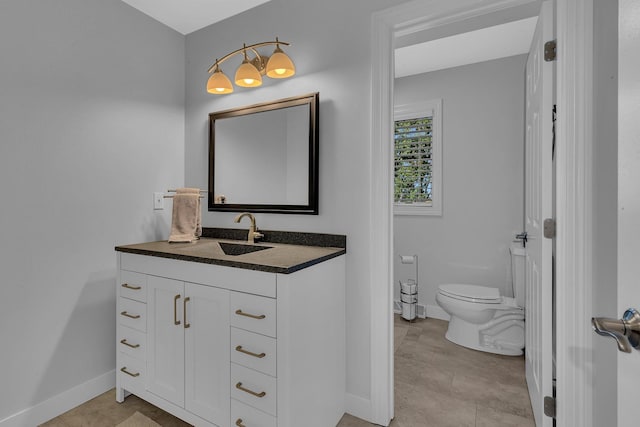 bathroom featuring baseboards, vanity, and toilet