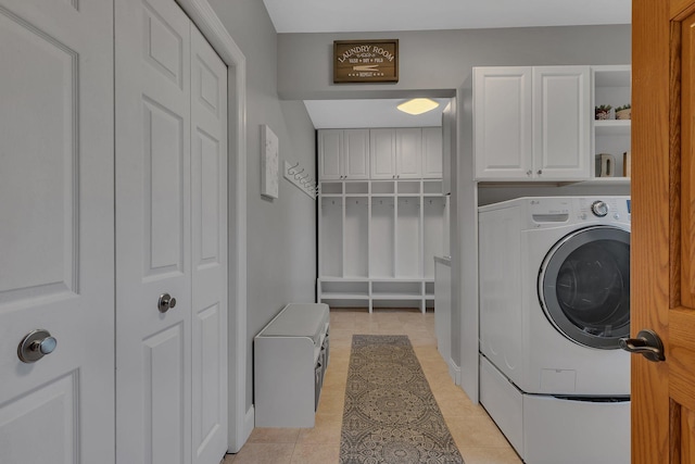 clothes washing area featuring washer and dryer, cabinet space, and light tile patterned floors