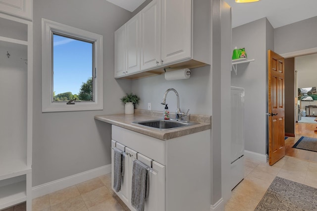 kitchen featuring light countertops, white cabinets, a sink, and baseboards