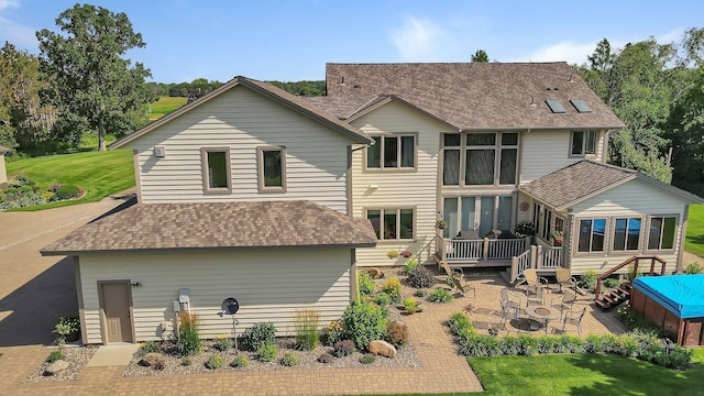 back of property with a patio area, roof with shingles, a lawn, and a deck