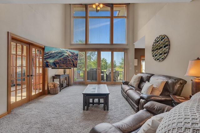 carpeted living area featuring a towering ceiling and french doors