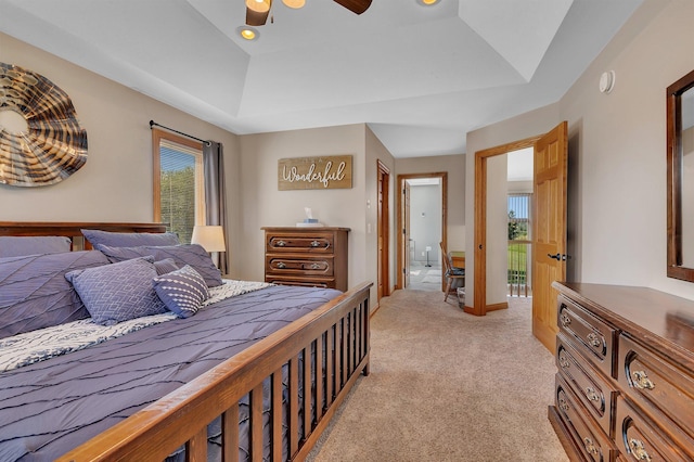 bedroom with a raised ceiling, light colored carpet, ceiling fan, and baseboards