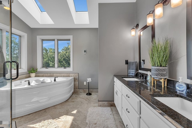 full bath with double vanity, lofted ceiling with skylight, a sink, and a bath