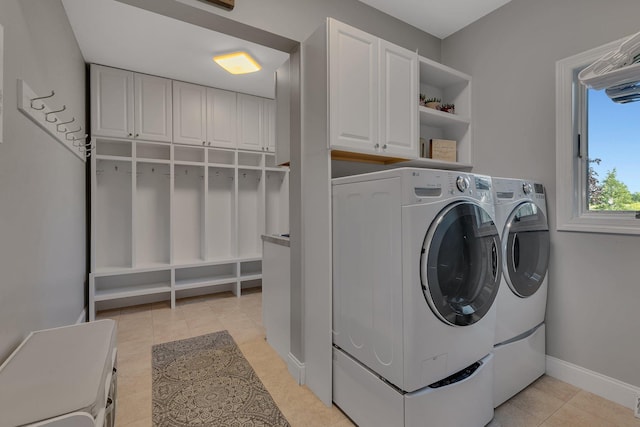 laundry area featuring cabinet space, light tile patterned floors, baseboards, and washer and dryer