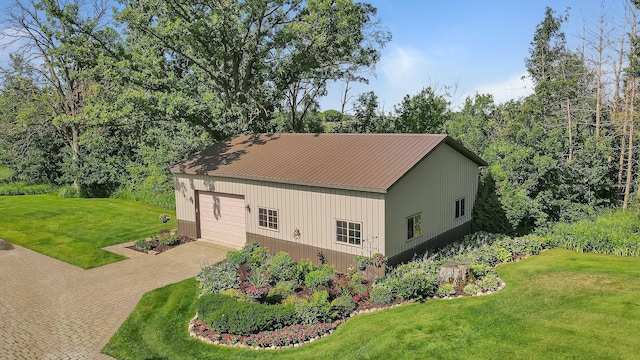 view of side of property with driveway, metal roof, and a lawn