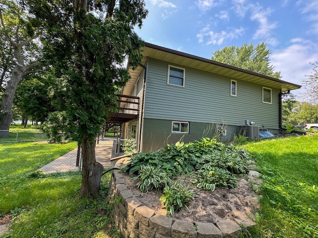 view of property exterior with a wooden deck, central AC, and a yard