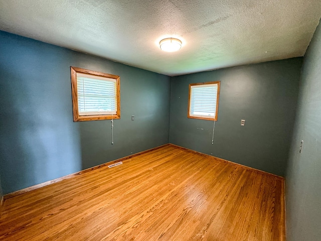 empty room featuring light wood-type flooring and a textured ceiling