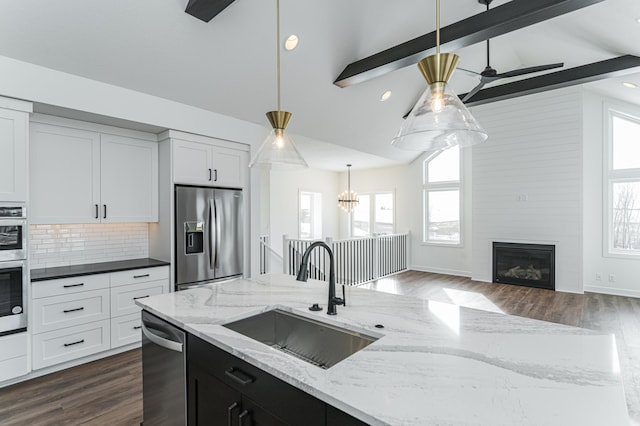 kitchen featuring stainless steel appliances, hardwood / wood-style floors, sink, a fireplace, and beamed ceiling