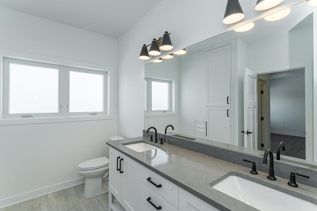 bathroom with double vanity, toilet, and hardwood / wood-style flooring