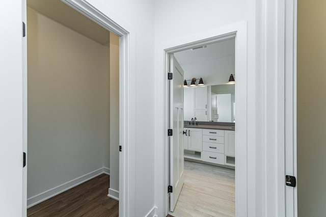 corridor with light wood-type flooring and sink