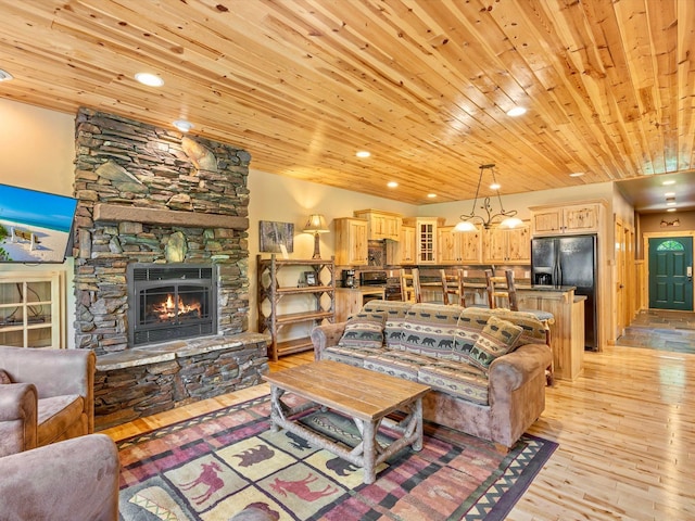 living room featuring wood ceiling, a fireplace, light hardwood / wood-style flooring, and a notable chandelier