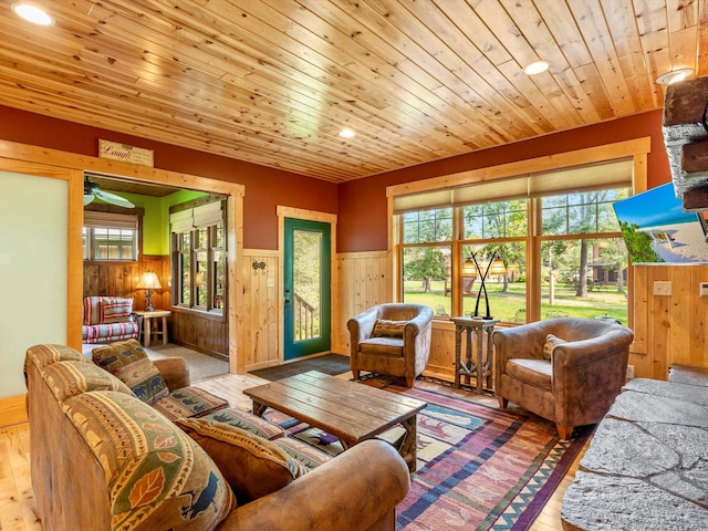 living room with a healthy amount of sunlight, wood ceiling, wooden walls, and light hardwood / wood-style flooring