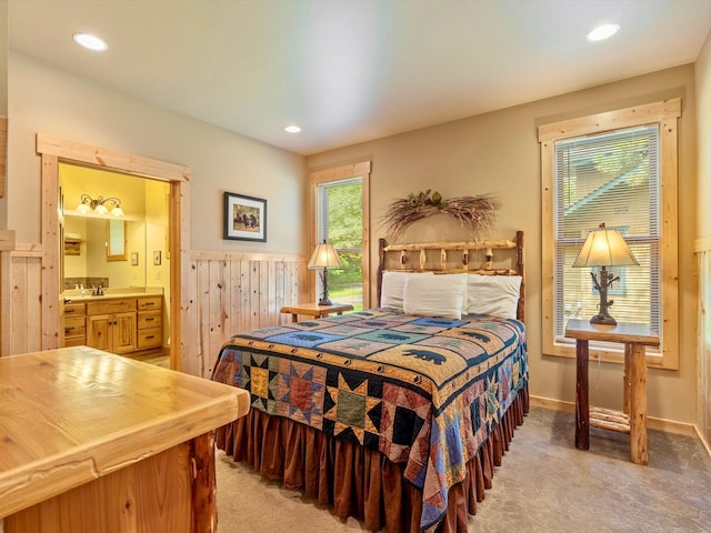 bedroom featuring connected bathroom, sink, and light carpet