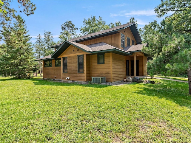 view of property exterior featuring roof with shingles, cooling unit, and a yard