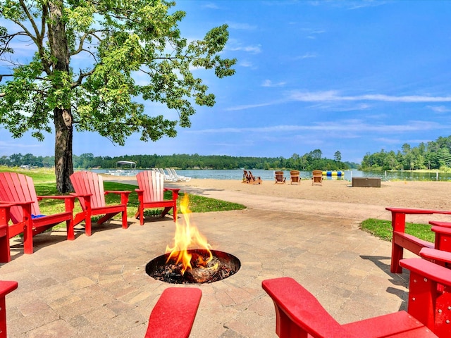 view of patio with a fire pit and a water view