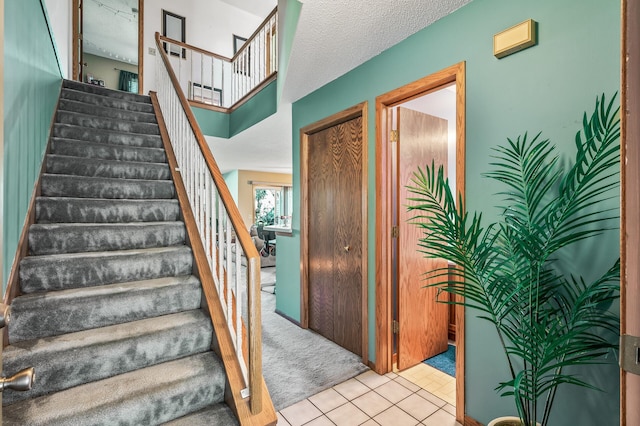 staircase with tile patterned floors and a textured ceiling