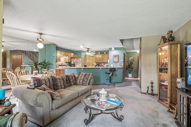 carpeted living room featuring ceiling fan and a textured ceiling