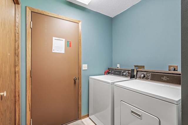 laundry room with light tile patterned flooring, washing machine and dryer, and a textured ceiling