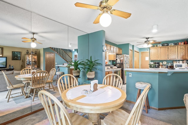 dining area with stairs, a textured ceiling, baseboards, and light colored carpet