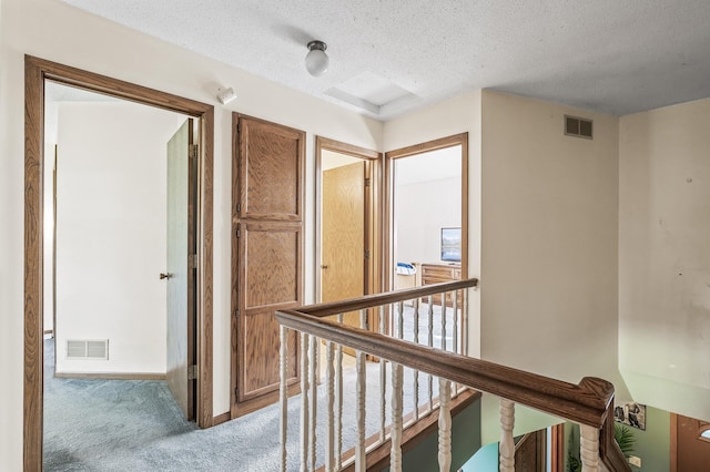 corridor with carpet and a textured ceiling