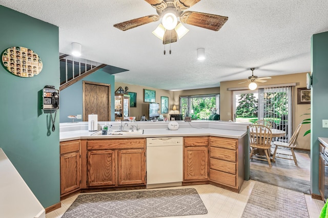 kitchen with dishwasher, sink, light tile patterned floors, kitchen peninsula, and ceiling fan